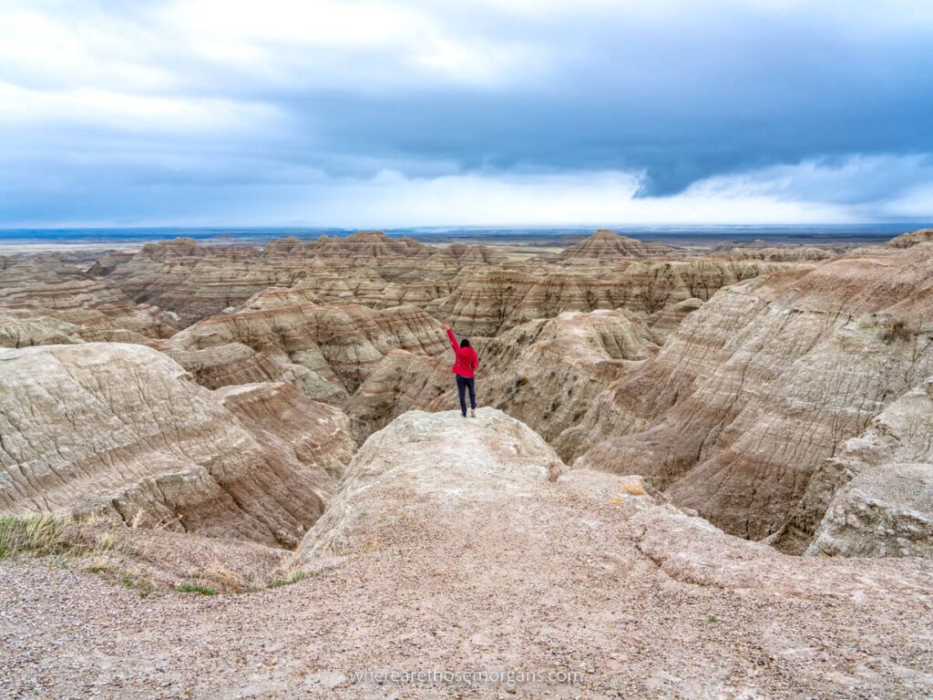 Hiker enjoying the view over Badlands national park unique landscape on a cloudy day