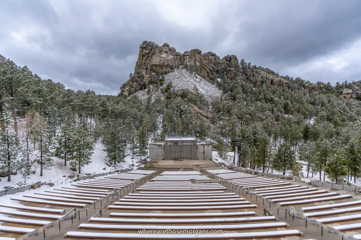 Outdoor amphitheater with rows of benches overlooking a national monument sculpture on a cloudy day