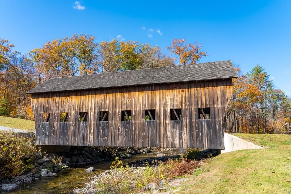 Side profile wooden structure over a stream in new england with blue sky