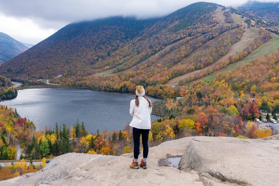 Stood on the edge of a rock slab with amazing views over Echo Lake and fall foliage trees in new hampshire franconia notch