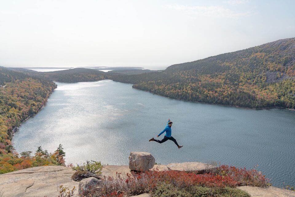 Where Are Those Morgans jumping from one rock to another at the summit of South Bubble trail one of the best hikes in acadia national park with lake background perspective photograph