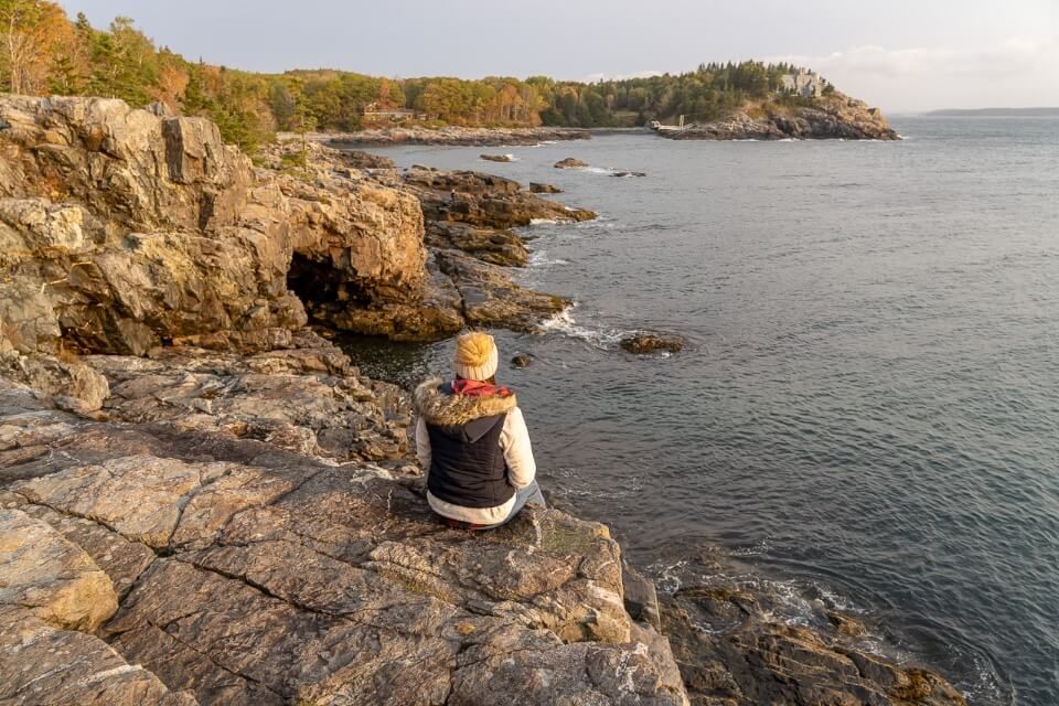 Woman sitting on the edge of a cliff in Acadia