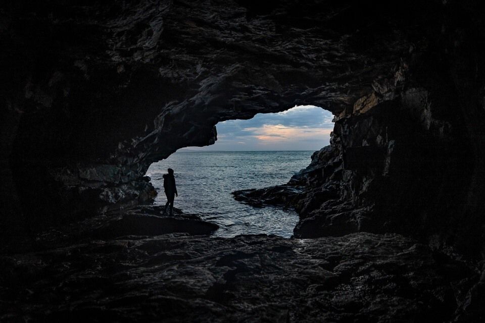 Hidden cave in Acadia National Park woman silhouetted against ocean at sunrise best things to do in acadia