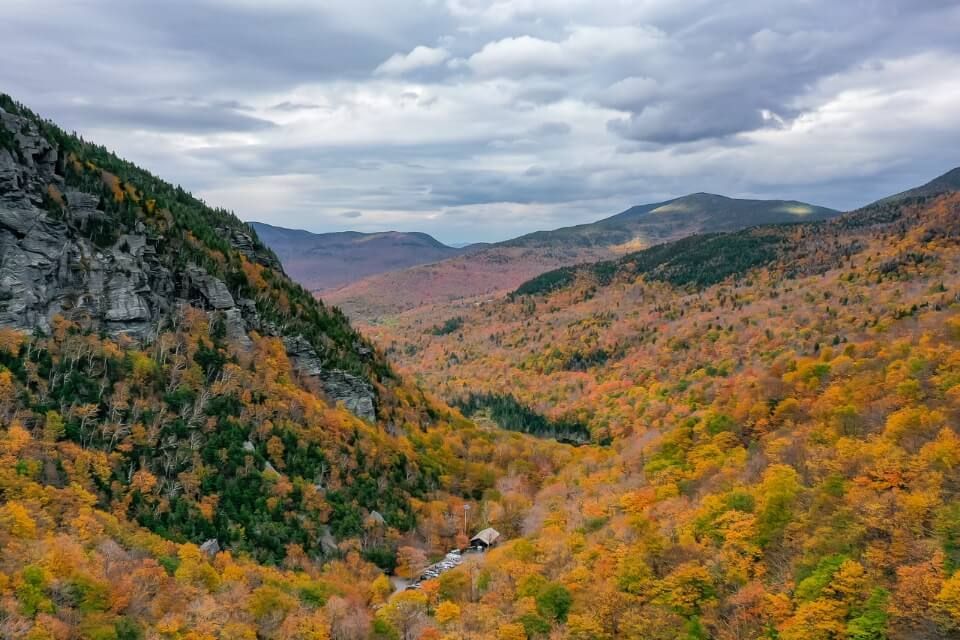 Stunning fall foliage colors yellows oranges reds and greens near mount mansfield looking down valley from smugglers notch drone