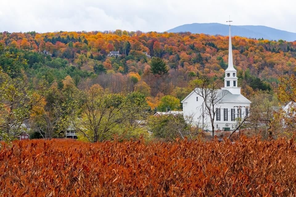 Famous white church in Stowe Vermont in fall foliage autumnal colors stunning photography and one of the best things to do in stowe VT