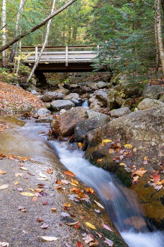 Stream and bridge with leaves on rocks in new hampshire