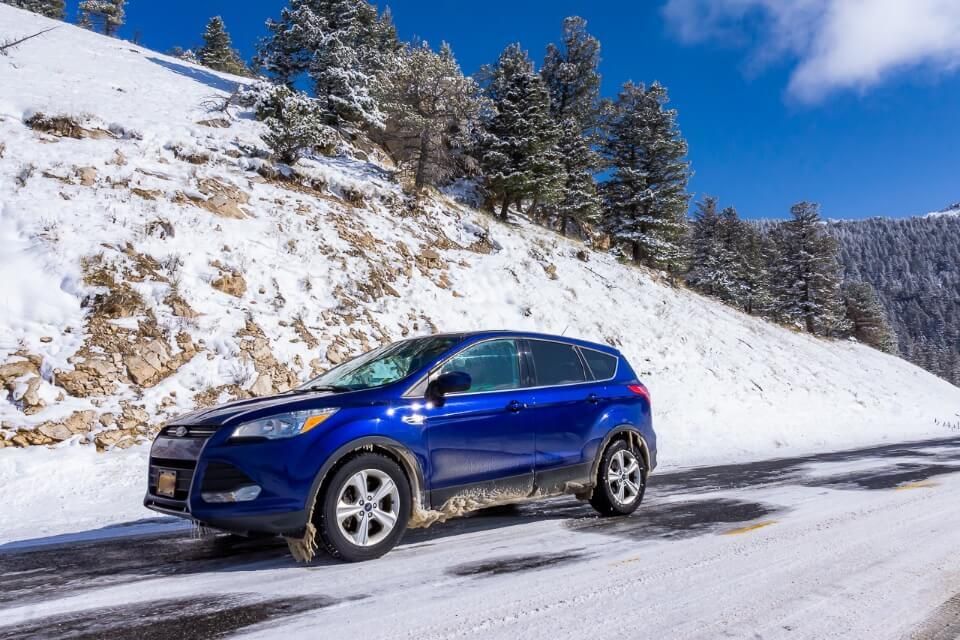 Car on snow near yellowstone national park road trip planner resource and how to plan the perfect road trip