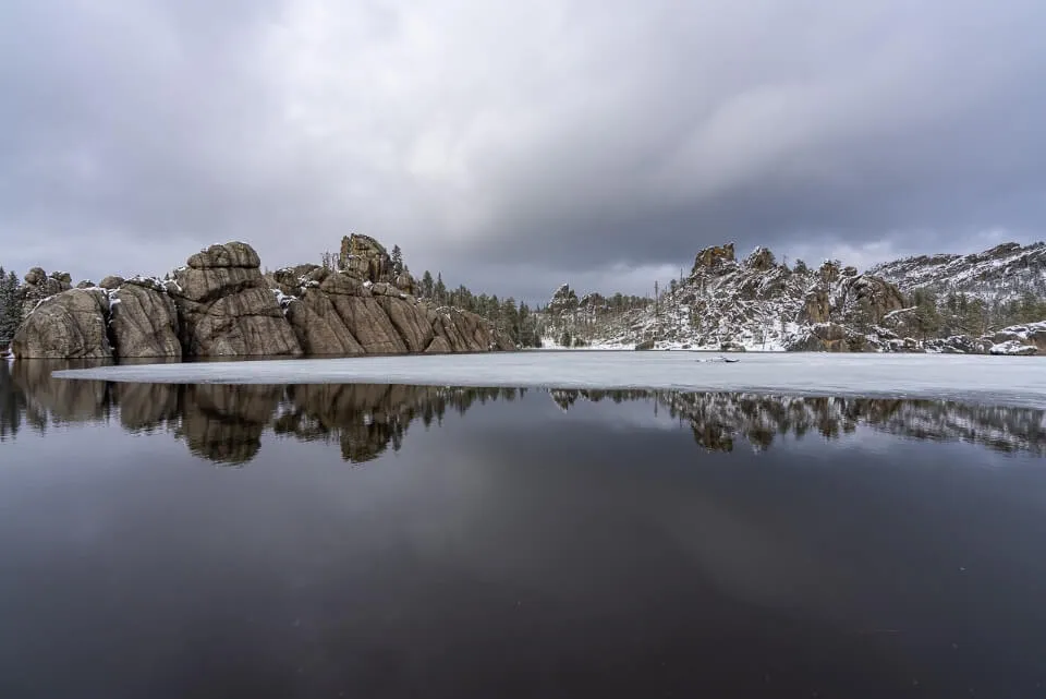 Sylvan Lake reflecting on still water with blowers and snow and ice