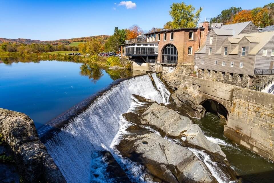 Quechee waterfall and riverside buildings on a sunny day in new england