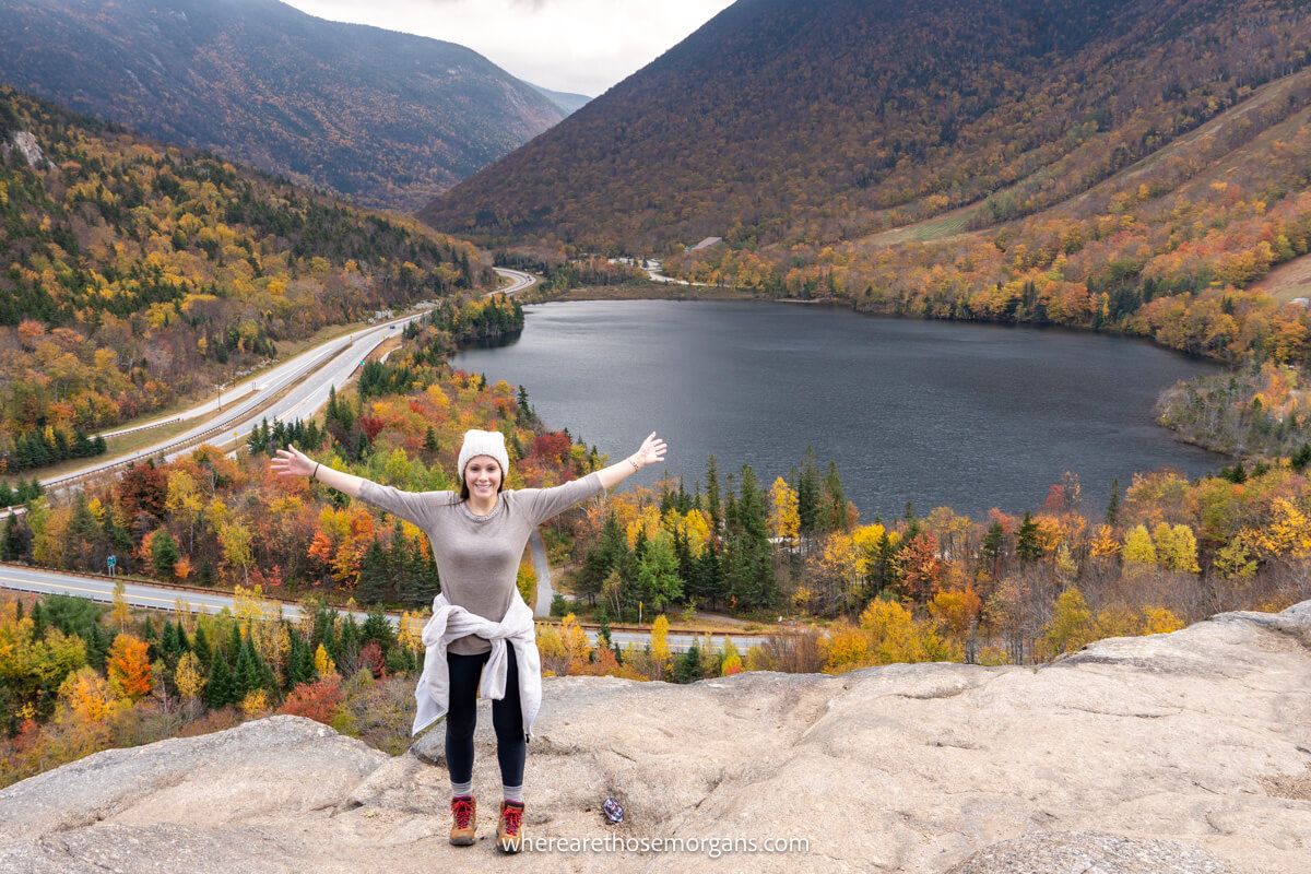 Hiker with arms stretched out at the summit of Artists Bluff in peak fall foliage season