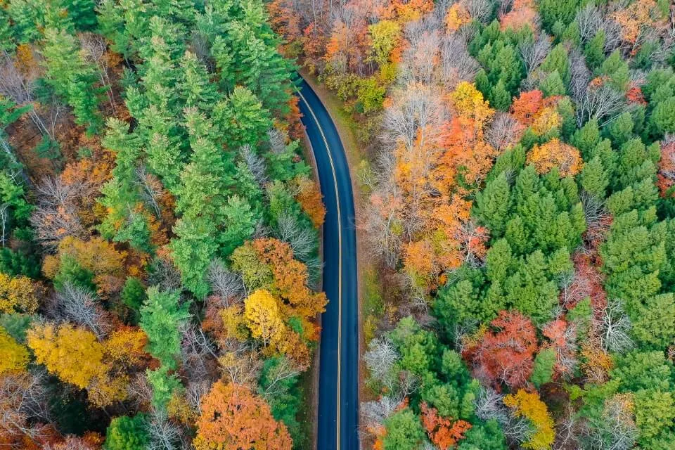 Kancamagus Highway in New Hampshire White Mountain National Forest is one of the most popular roads to drive on a new england fall road trip drone shot stunning colors