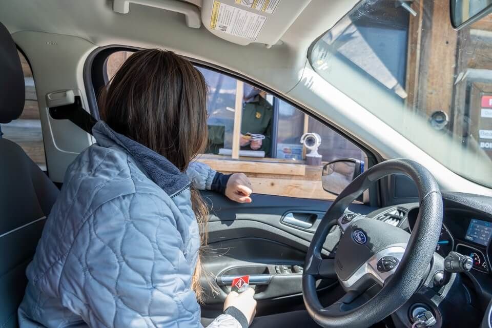 Driver of car entering national park in wyoming at official entrance with annual pass