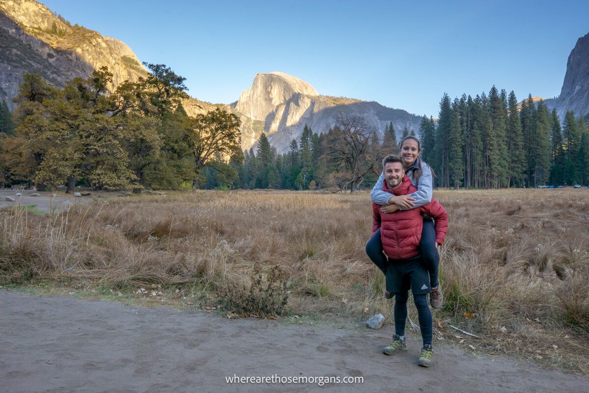 Woman jumping on man's shoulders with views of Yosemite Valley and Half Dome in the background