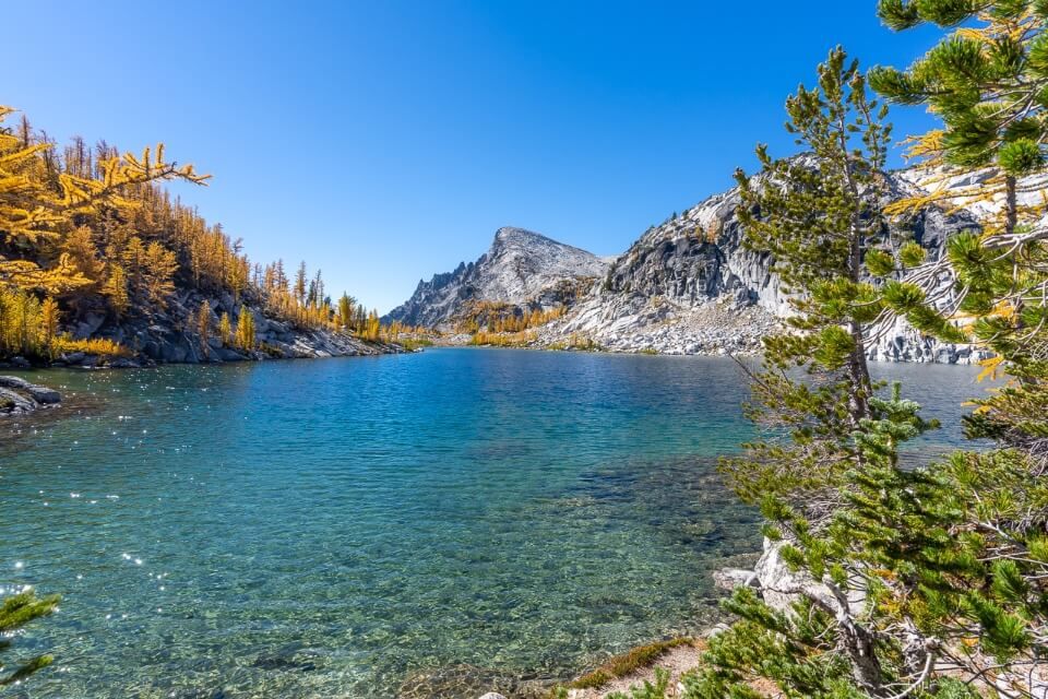 Day hiking the Enchantments trail in washington clear blue perfection lake with golden larches in peak where are those morgans hiking bucket list us trail