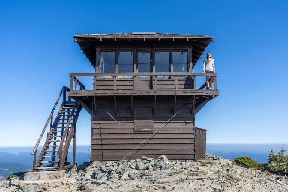 Mt Fremont Fire Lookout Tower at the summit of an amazing hike overlooking mt Rainier volcano Kristen standing on wooden structure alone