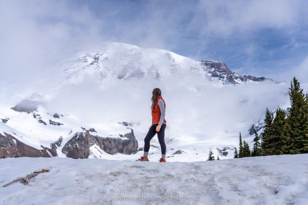 Hiker on a snowy trail with huge volcano behind