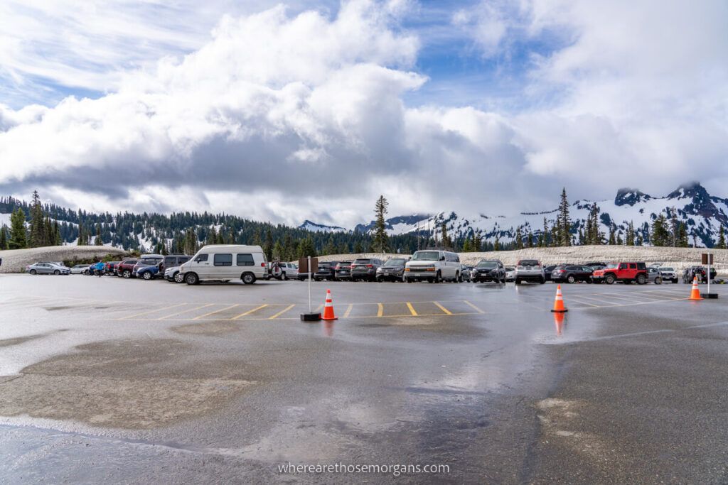 Parking lot at Paradise in Mt Rainier National Park with water on the ground and puffy clouds in the sky