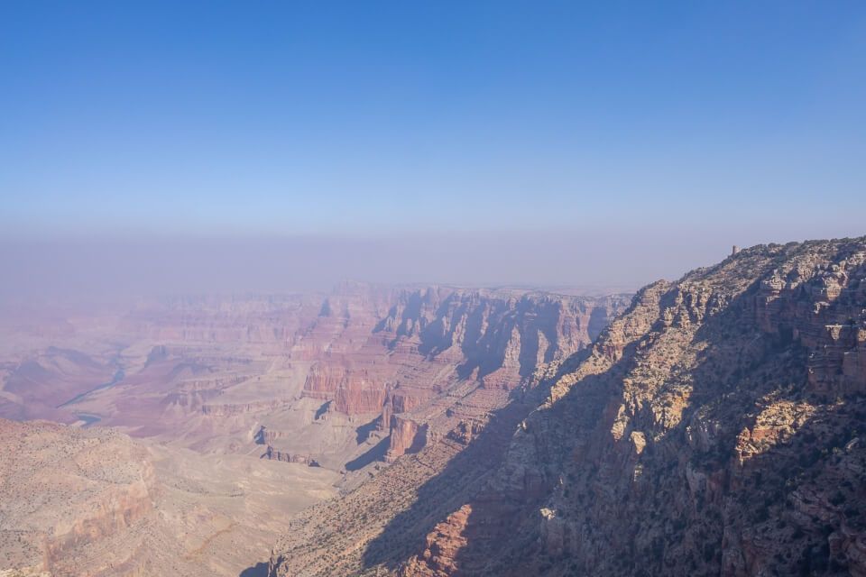 Navajo Point on a very hazy day in northern arizona with stone watchtower in distance