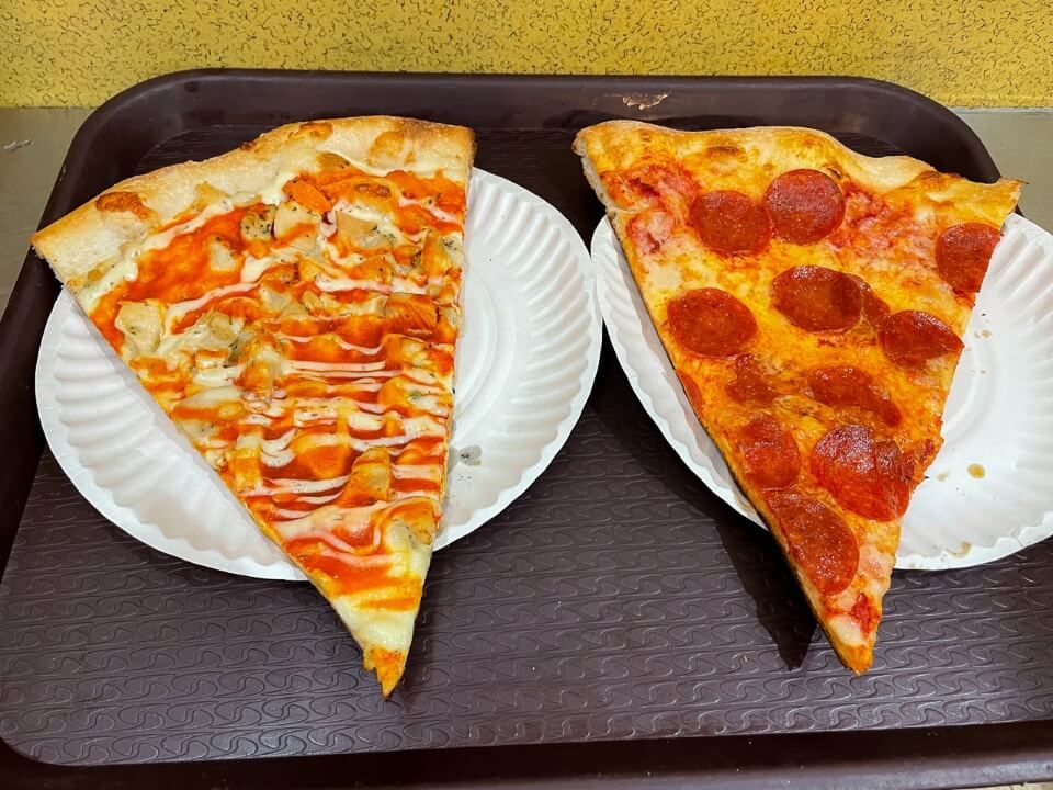 One slice of buffalo chicken pizza and one slice of pepperoni pizza in NYC