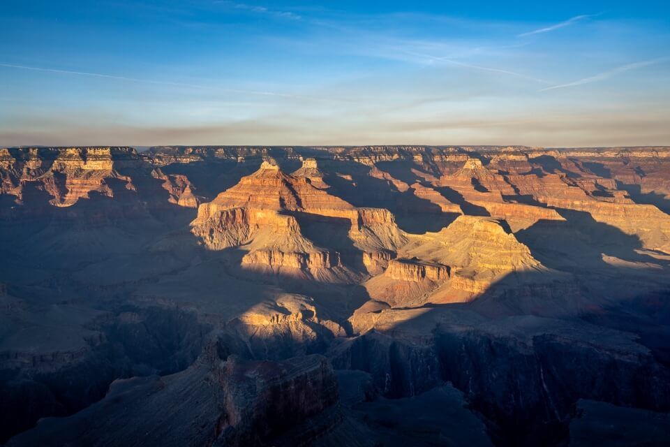 Grand Canyon national park glowing under sunlight with canyon in shadow and blue sky perfect weather and best time to visit