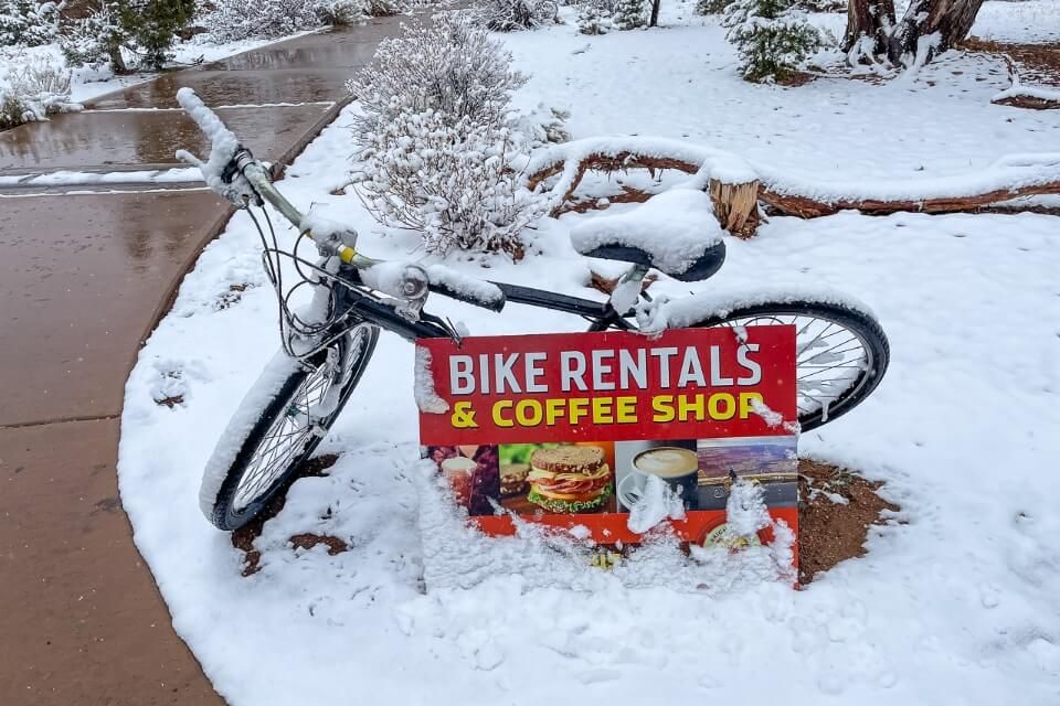 Bicycle covered in snow advertising rentals and coffee shop