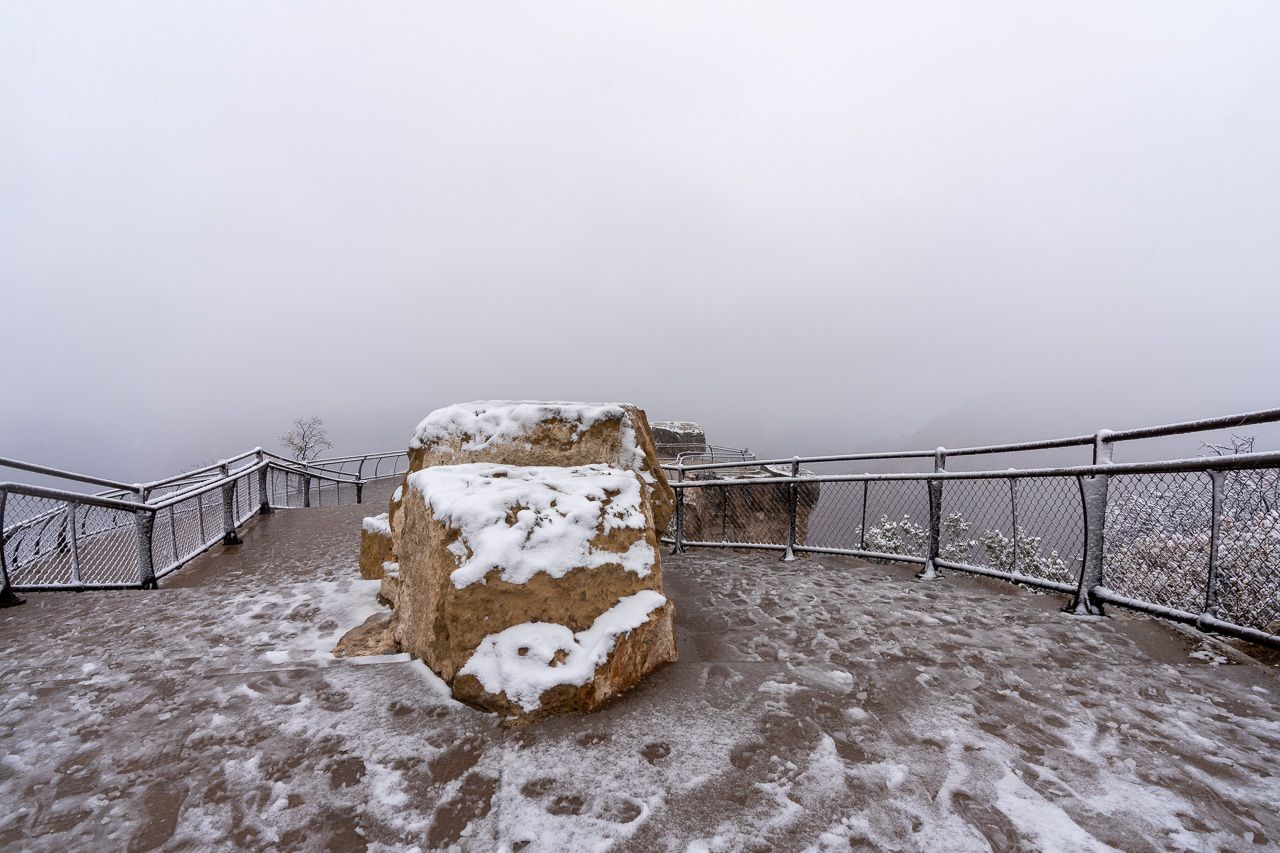 Mather Point one of the most popular overlooks in grand canyon national park is completely empty and covered in snow during december winter fog