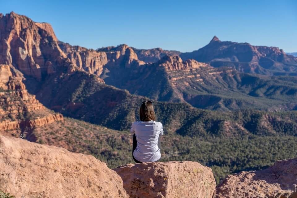 Hiker sat enjoying the view in Zion national park in utah gorgeous blue sky sunny winters day