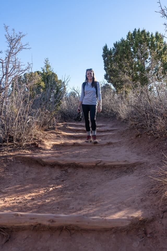 Hiker on a path with wooden poles for support with dirt path on a sunny day in utah