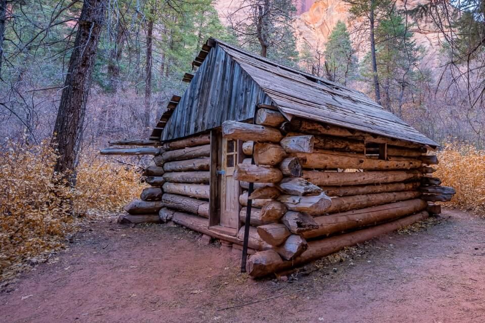 Stunning log cabin lodge along Taylor Creek Trail in Kolob Canyon area of Zion national park surrounded by yellow long grass and orange rocks