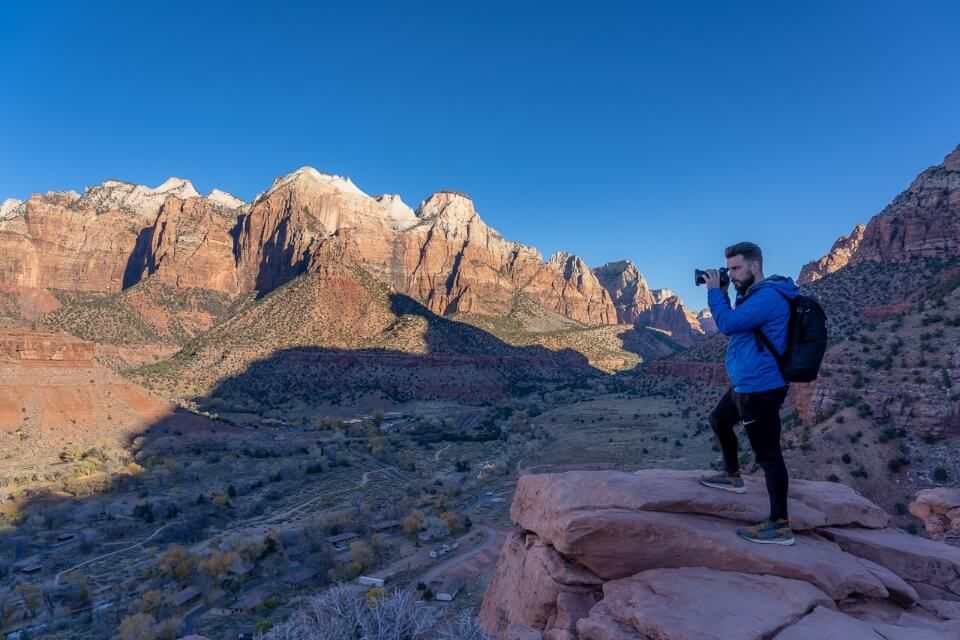 Hiking photographer at sunrise The Watchman Trail Overlook sunrise in Zion National Park