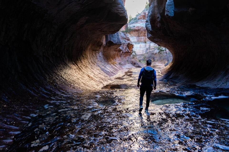 Hiking through the Subway in Utah with deep shadows before sunlight illuminates the tunnel formation