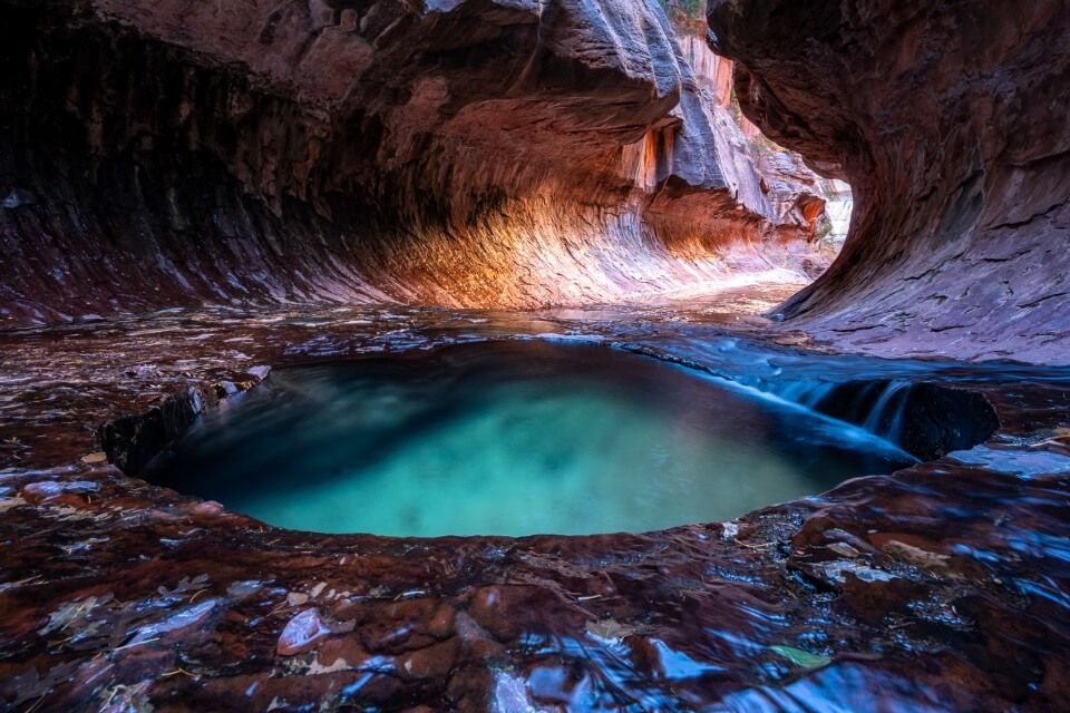 Extraordinary colors and rock formations at the end of the Subway hike in Zion National Park orange light illuminating the tunnel and emerald green pools