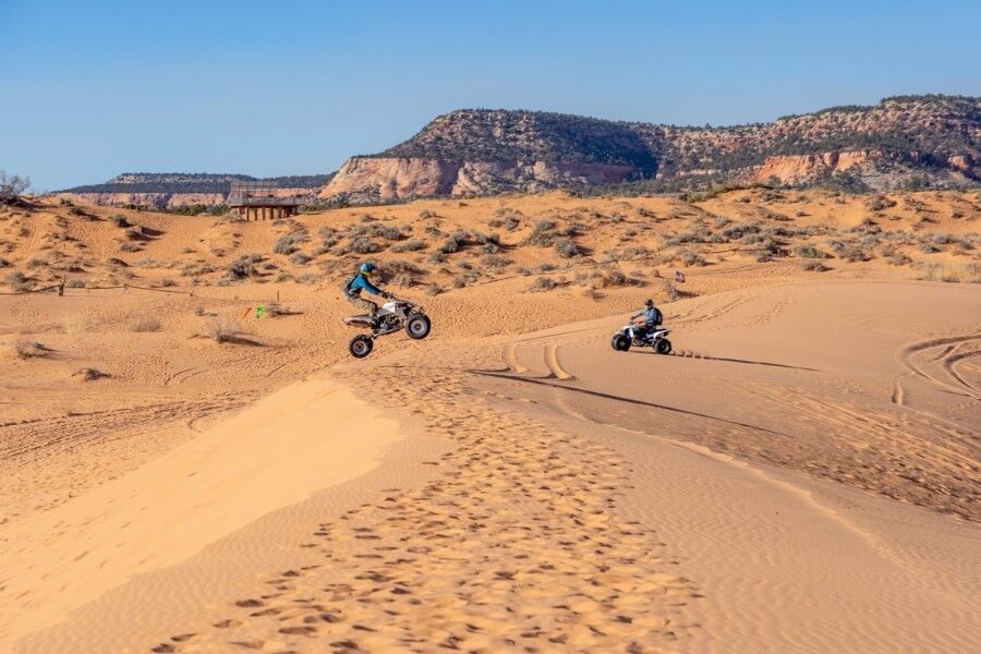 ATV driving at coral pink sand dunes state park near Kanab Utah OHVs jumping oner sand dunes with air time