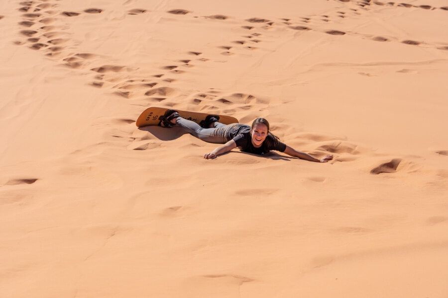 Fallen sand boarder struggling in deep sand but laughing