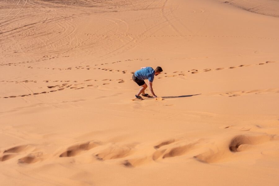 Sliding down sandy hills on boards near Kanab Utah touching the sand