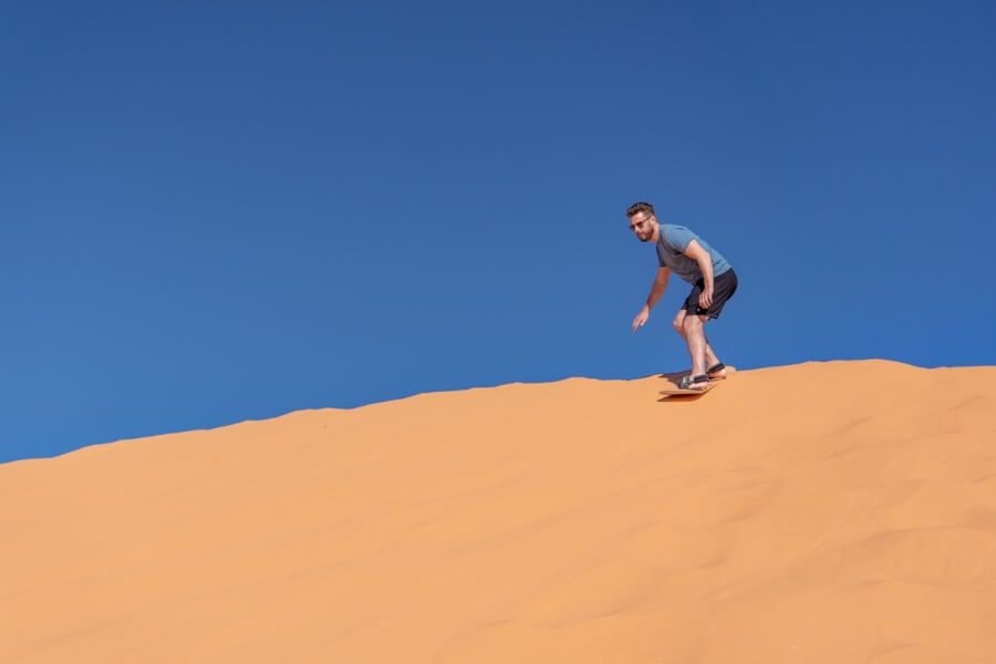 Sandboarder at the top of a sand dune with brilliant blue sky in coral pink sand dunes state park Utah