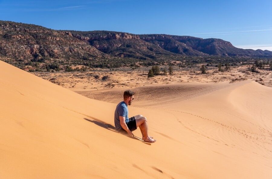 Sledding down a sand dune in coral pink sand dunes state park near Kanab Utah on a beautiful sunny day in December