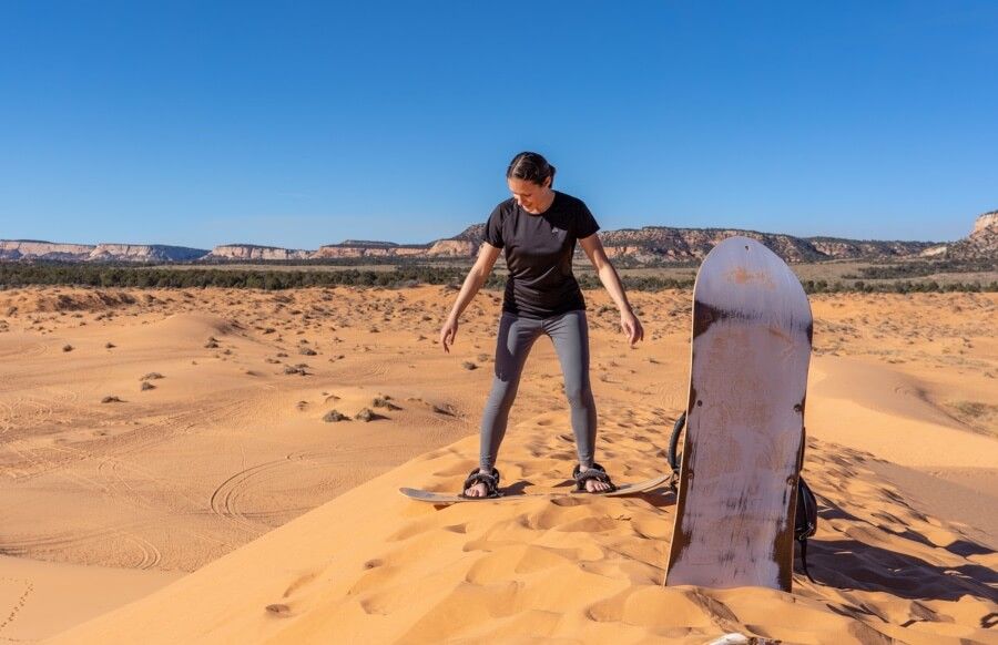 Starting a sandboarding run down yellow pink dunes in Utah