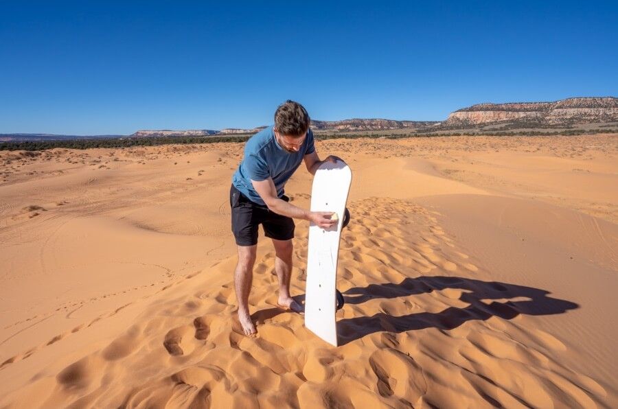 Waxing a sandboard on a sand dune in coral pink sand dunes state park Kanab Utah