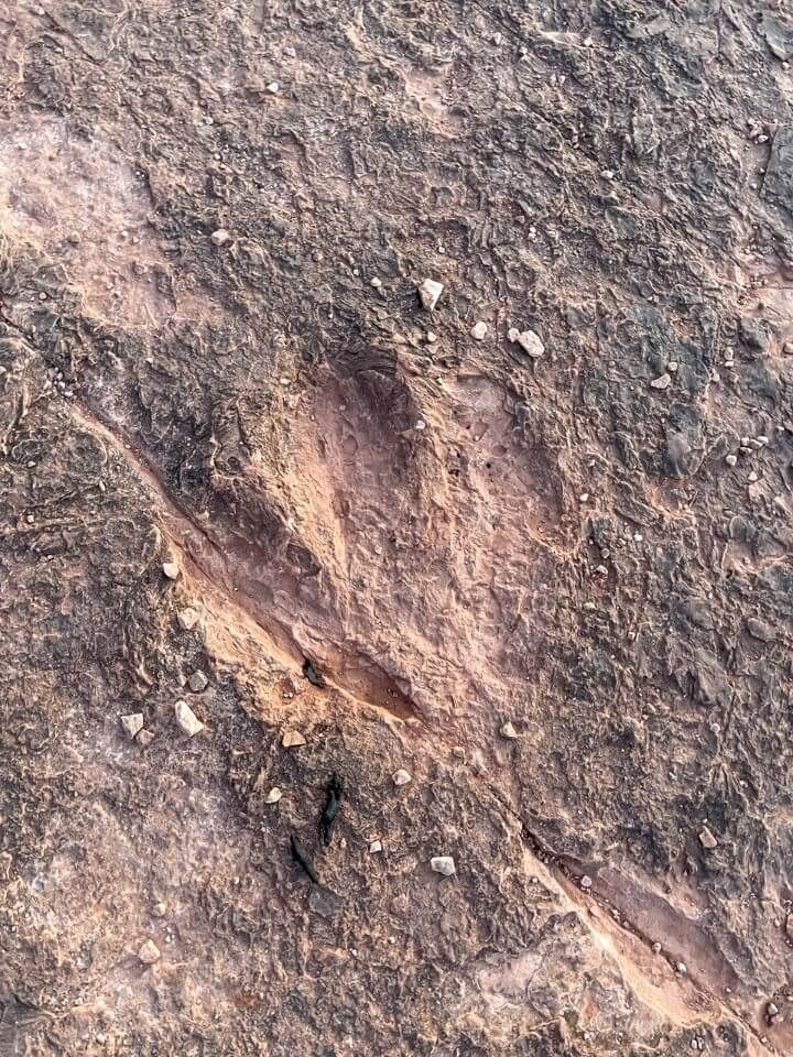 Deep marking in gray rock with small stones around indent