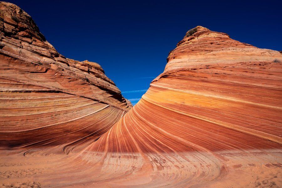 Deep blue sky behind orange red and pink smooth domes at the end of the wave hike in arizona