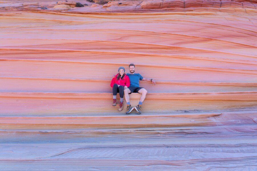 Hikers sat on a ledge of colorful layers of rock