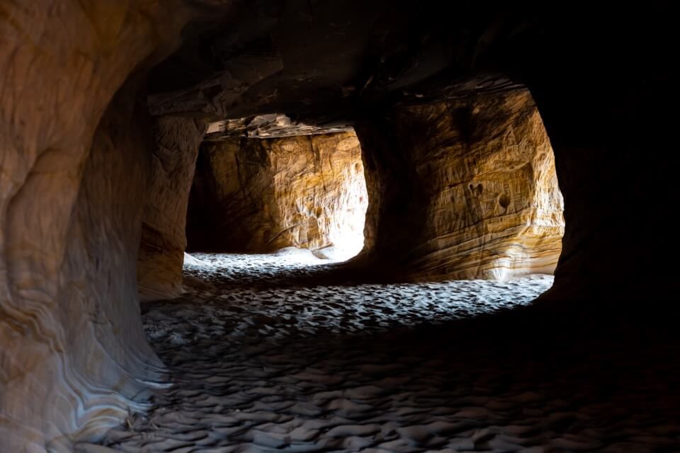 Sunlight beaming into sand caves near Kanab Utah called Moqui Caverns deep shadows cast on sand