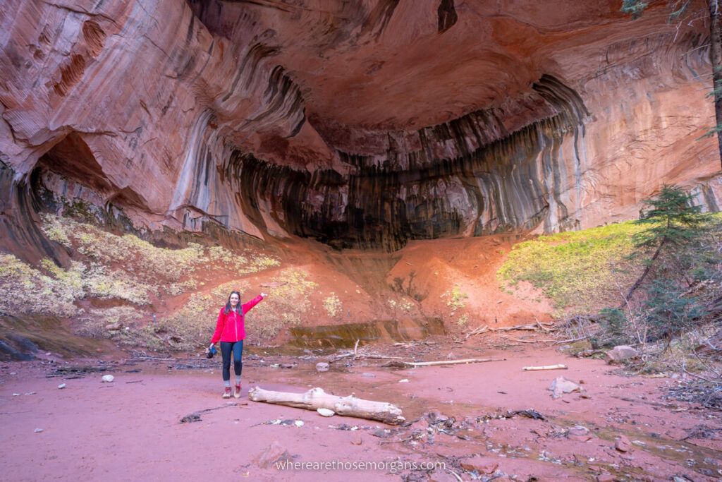 Woman pointing into a huge alcove wall at the end of a trail in Utah