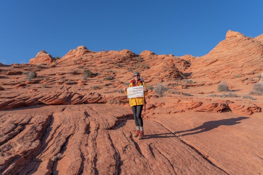 Hiker with map on orange sandy rocks and blue sky