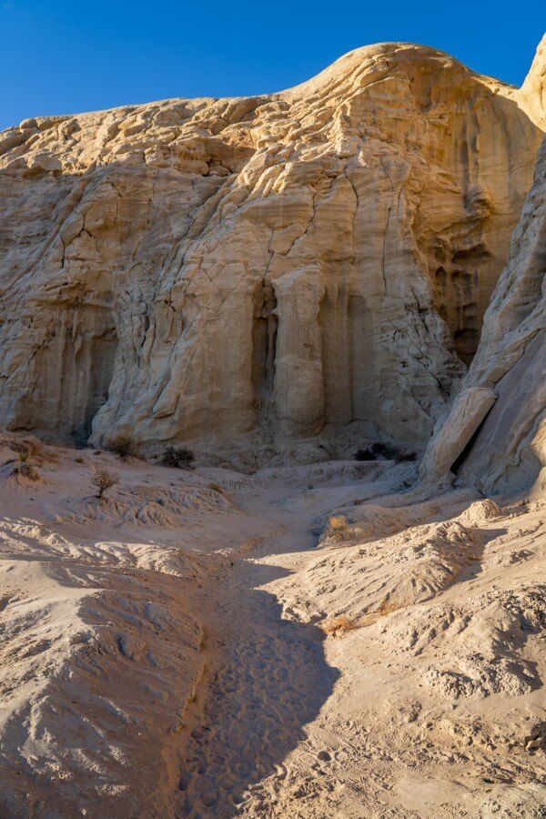 Chambers of rock eroded from a huge cliff colored yellow under sunlight