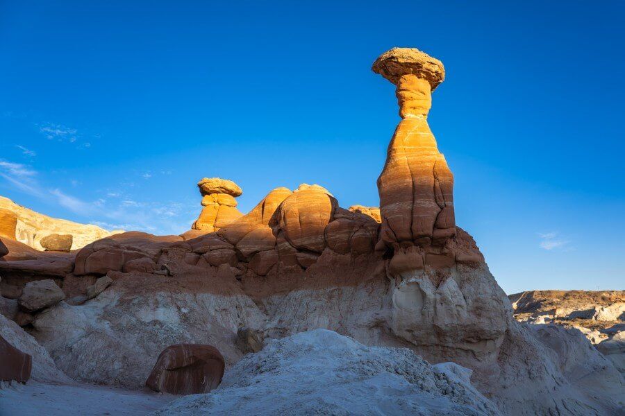Toadstool hoodoos mushroom shaped formations in southern utah at sunset half covered in light and half in shadow with bright blue sky