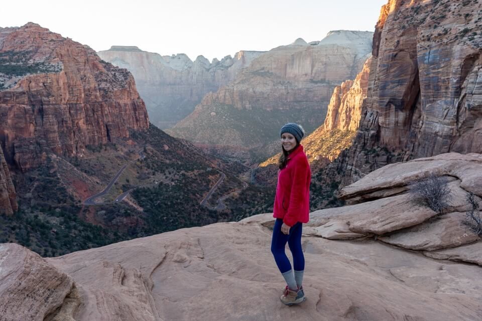 Hiker at zion canyon overlook during a cold winter sunset in December wearing a fleece and wooly hat