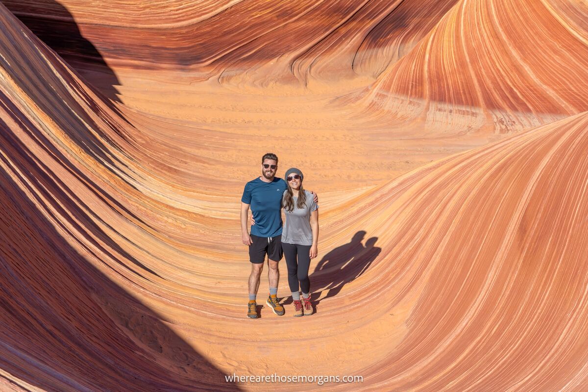 Photo of a couple standing alone inside a red rock formation with swirling sediment patterns