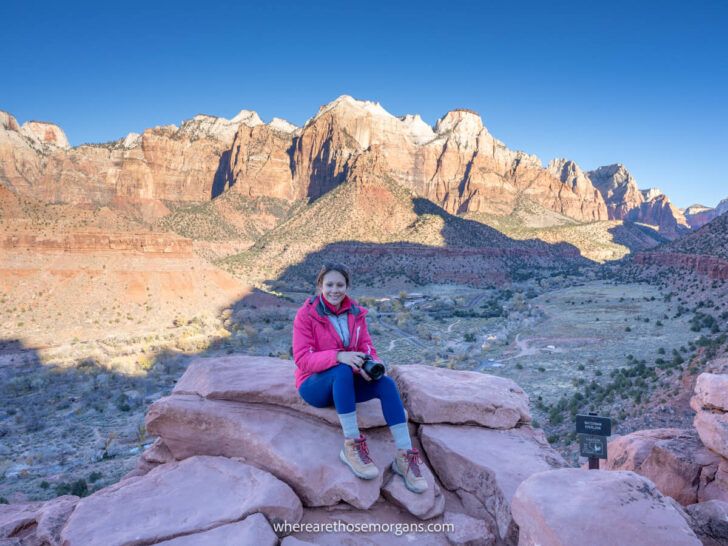 Photo of a hiker at the summit of The Watchman Trail at sunrise in Zion National Park on a clear but cold morning in winter